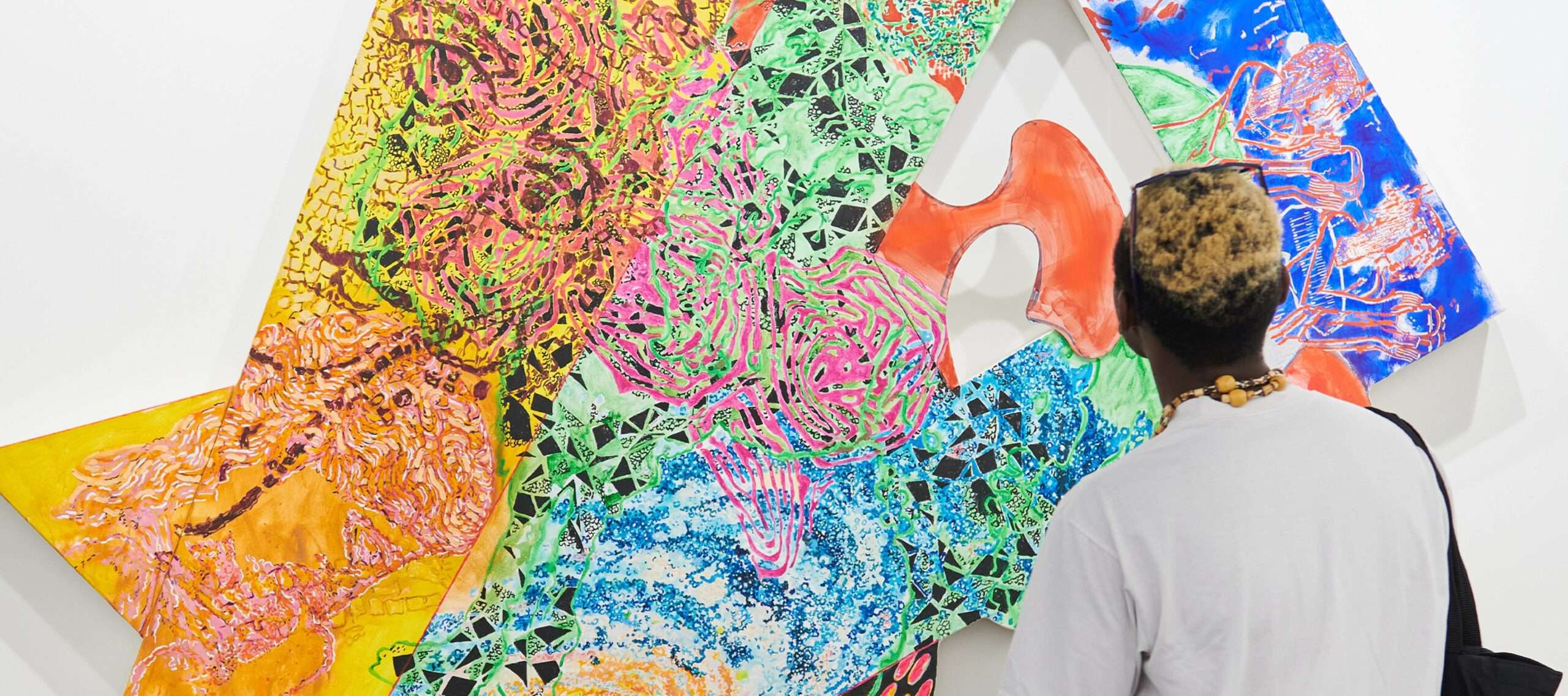 A man looks at an abstract colourful artwork at Art Basel.