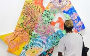 A man looks at an abstract colourful artwork at Art Basel.